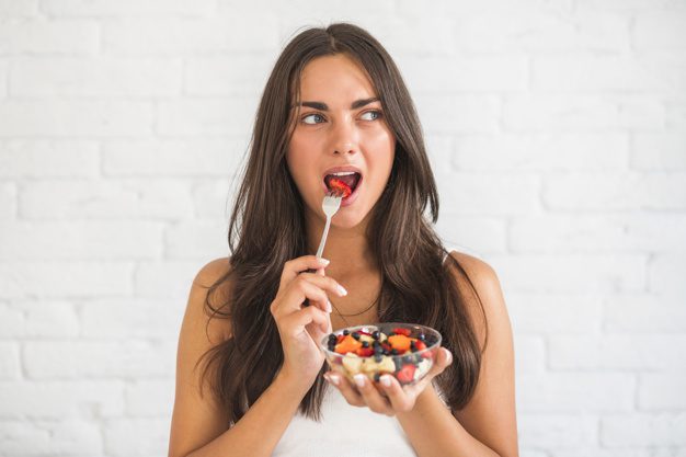 woman eating frui salad with fork